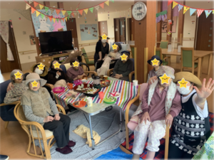 入居者が参加するレク活動。花飾りと装飾で彩られた共用スペースでの集団行事の様子。